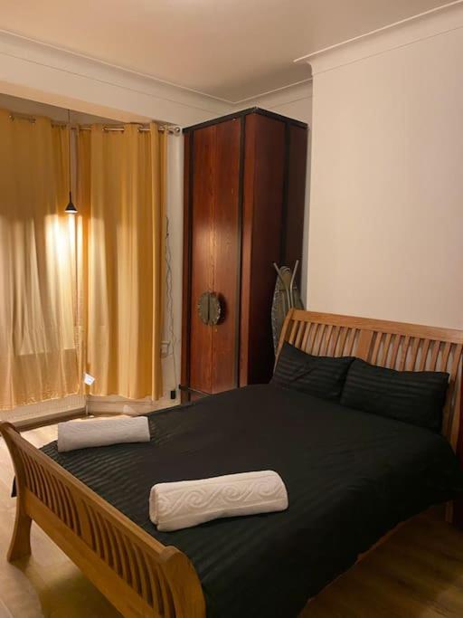 - une chambre avec un grand lit noir et 2 serviettes dans l'établissement (023) Lovely 2 bedroom house London, à Londres