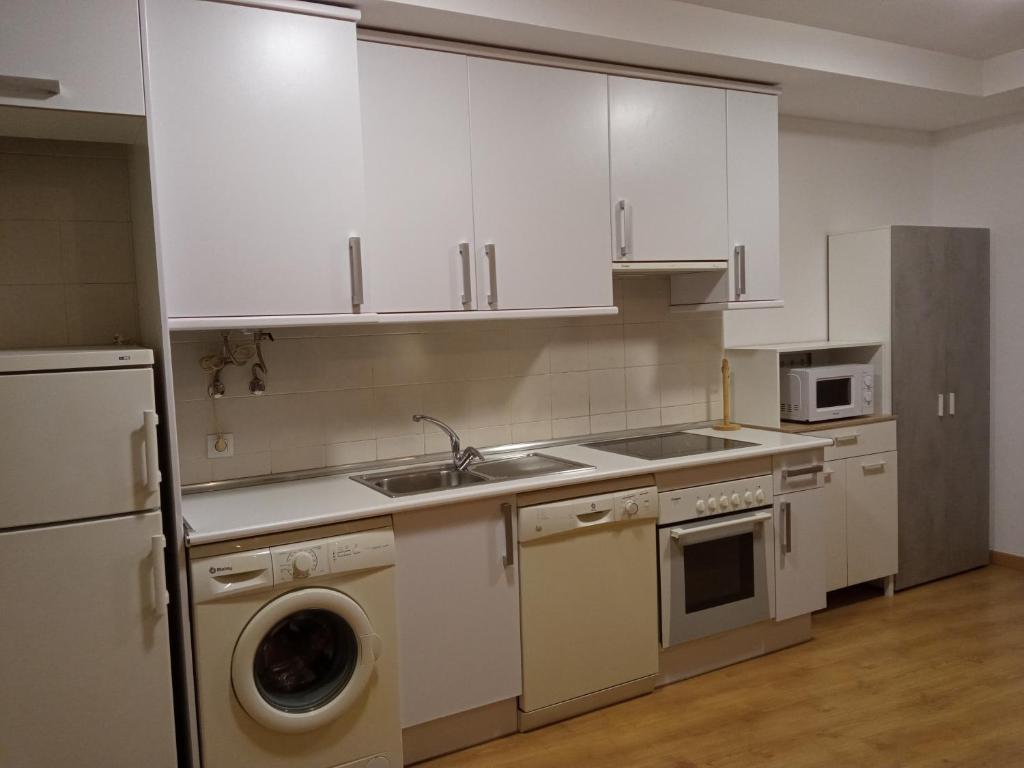 cocina con armarios blancos, fregadero y lavavajillas en Apartamento Casa Leonora, en Panticosa