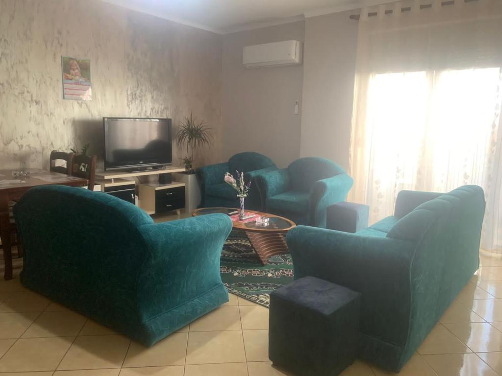 a living room with blue chairs and a tv at Guest House Fier in Fier