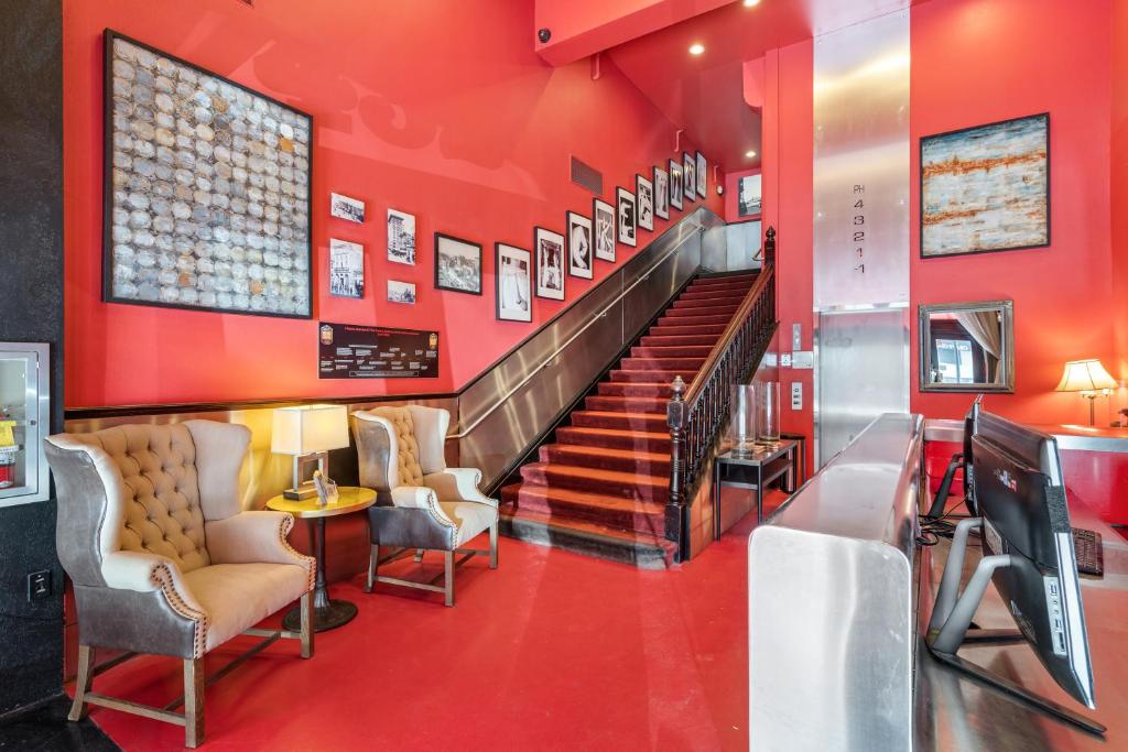 a lobby with a staircase with red walls and chairs at The Keating Hotel in San Diego