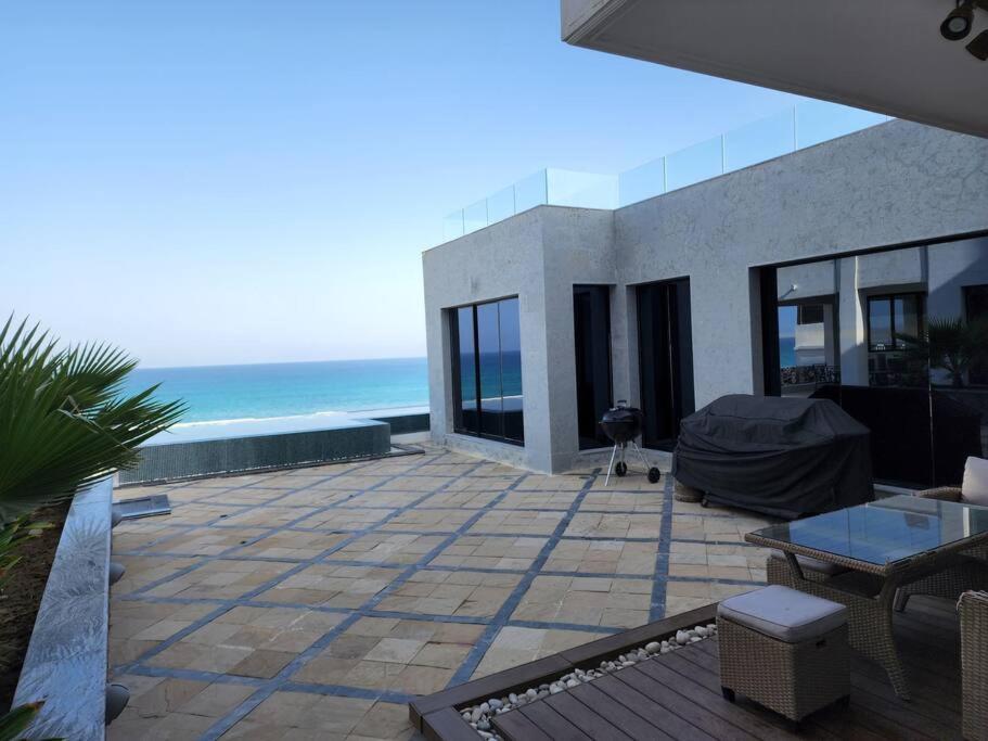 uma casa com um pátio com o oceano ao fundo em Wadi Shab/Fins Villa em Fins