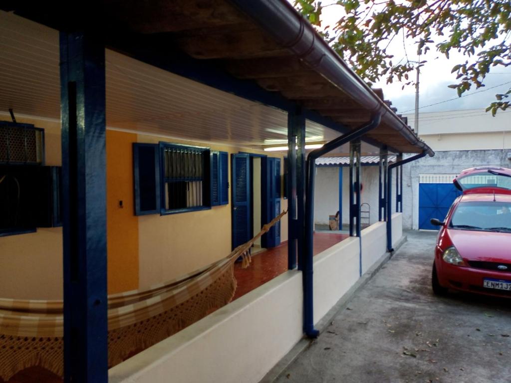 un edificio con un coche aparcado en un aparcamiento en Hostel Pé na praia - Quartos e Barracas Camping en Caraguatatuba
