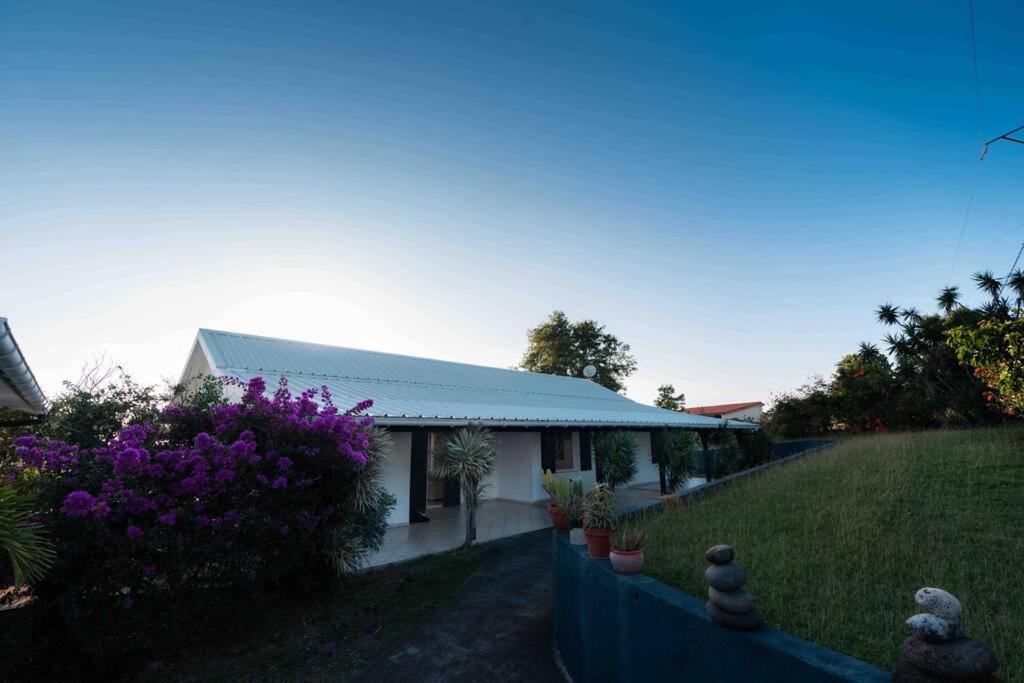 a white house with purple flowers in a yard at YOU WELCOME VILLA in Case-Pilote