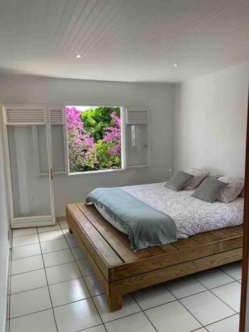 a bedroom with a bed and a window with pink flowers at YOU WELCOME VILLA in Case-Pilote