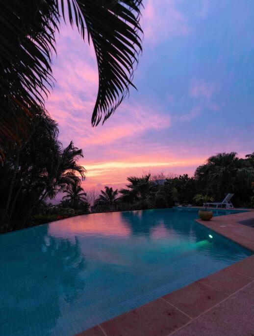 a large swimming pool with a sunset in the background at YOU WELCOME VILLA in Case-Pilote