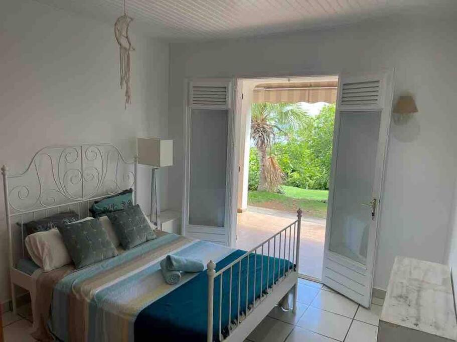 a bedroom with a bed and a sliding glass door at YOU WELCOME VILLA in Case-Pilote