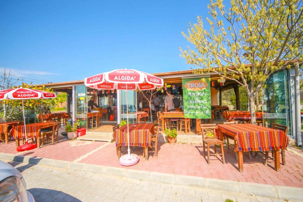 an outdoor restaurant with tables and chairs and umbrellas at Troia Pension in Akçapınar