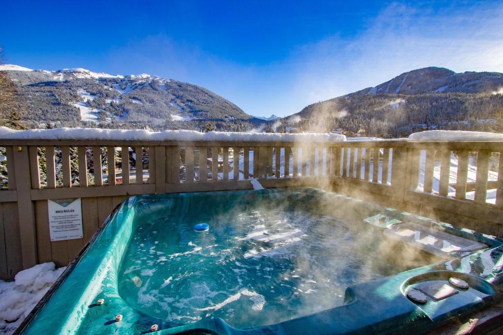 a hot tub on a deck with snow covered mountains at The Royal Suite - Village Penthouse, Private Hot Tub with Mountain Views in Whistler