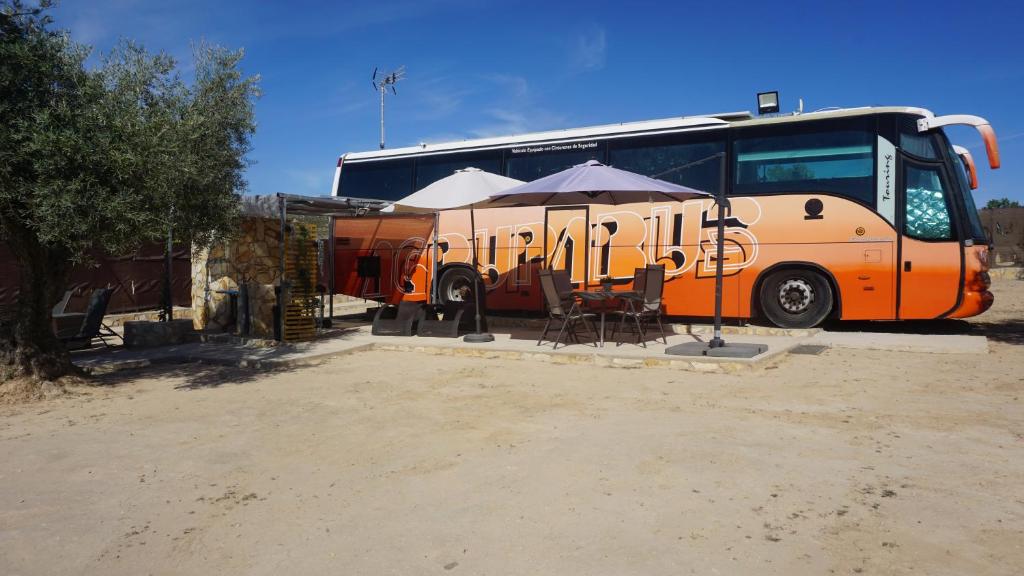 an orange bus parked next to a table and umbrella at cuchibus in Madrid