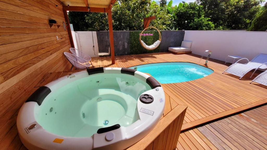 a bath tub sitting on a deck next to a pool at Casa 4 quartos com Piscina e Jacuzzi em Jurerê in Florianópolis