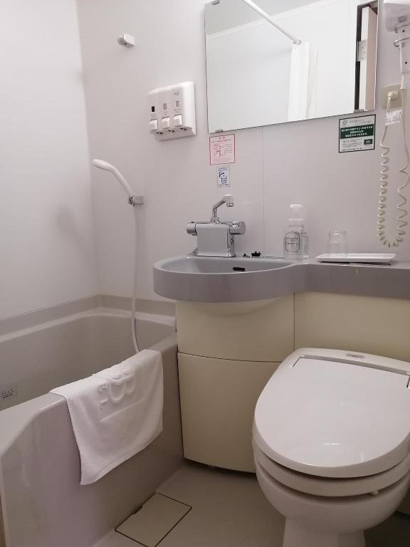 a bathroom with a toilet and a sink and a tub at Washington R&B Hotel Hachioji in Hachioji