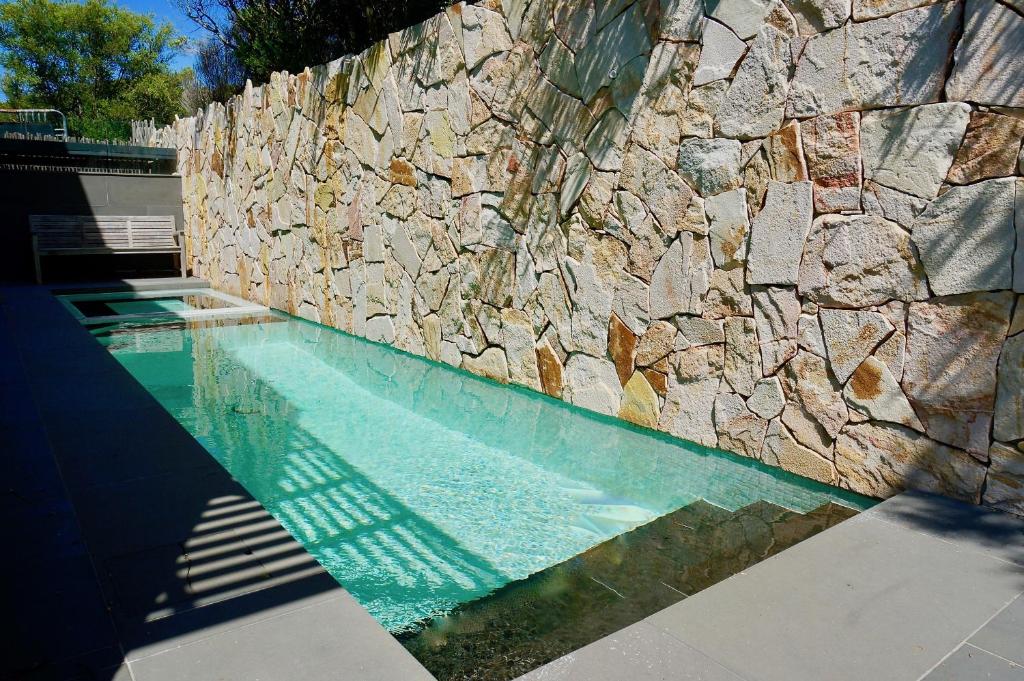 a swimming pool next to a stone wall at Sand Dunes in Point Lonsdale