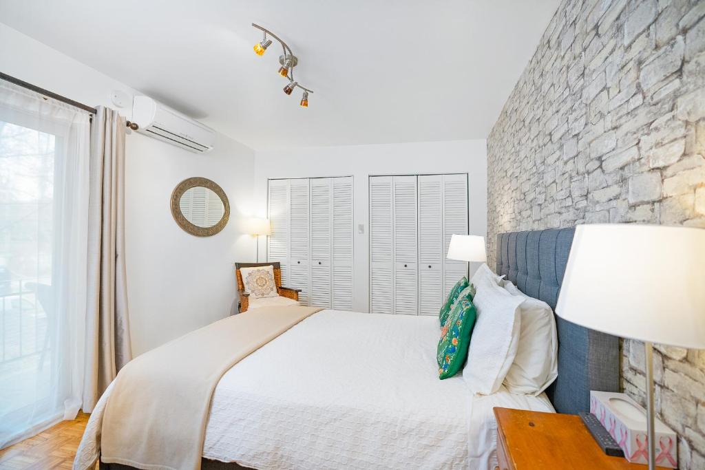 a bedroom with a white bed and a stone wall at Accueil Chez Francois in Montreal