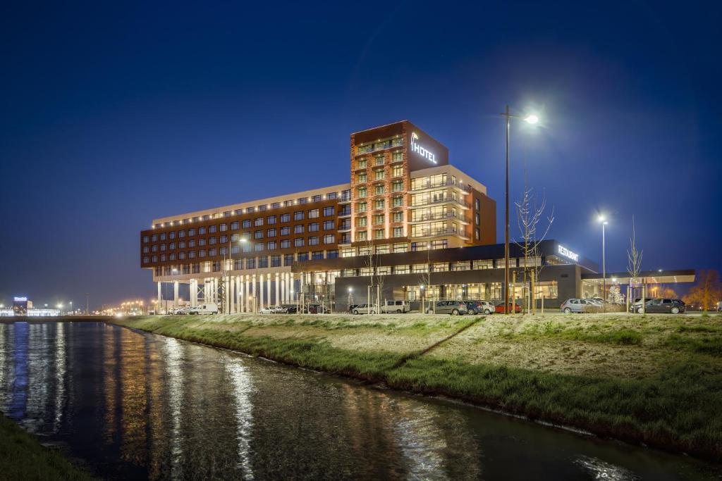 ein großes Gebäude neben einem Fluss in der Nacht in der Unterkunft Van Der Valk Hotel Zwolle in Zwolle