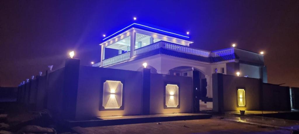 ein Haus mit blauen Lichtern darüber in der Nacht in der Unterkunft Smart Chalet:سمارت شالية in Salalah