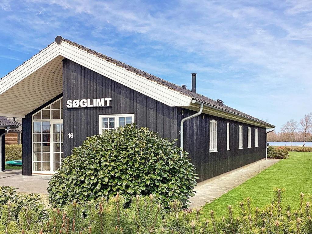 un bâtiment noir avec un panneau sur son côté dans l'établissement 10 person holiday home in Ansager, à Ansager