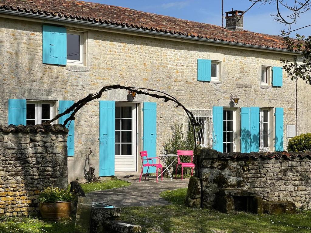 une vieille maison en briques avec des volets bleus et un patio dans l'établissement Vacances aux Petites Rivières, à Saint-Loup-de-Saintonge