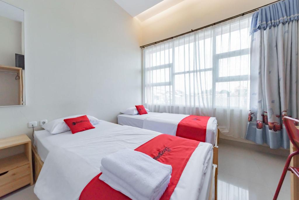 2 camas en una habitación con ventana en RedDoorz Syariah near DPRD Kabupaten Subang, en Subang