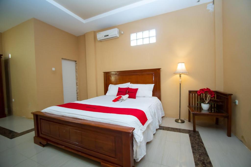 1 dormitorio con 1 cama grande con almohadas rojas en RedDoorz Syariah @ Jalan Gajah Mada Meulaboh en Meulaboh