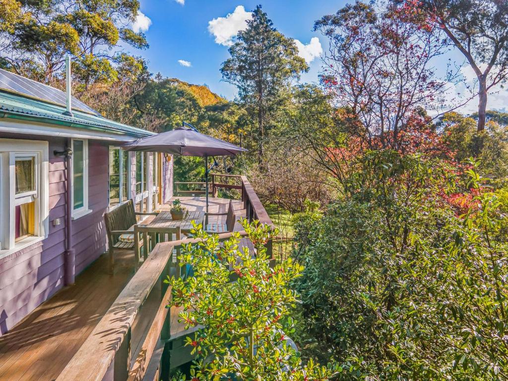 a deck with a table and an umbrella on a house at Cooee Cottage in Blackheath