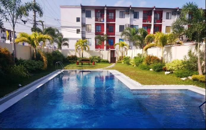 a large blue swimming pool in front of a building at The Red Room 2bed room Condo in Imus