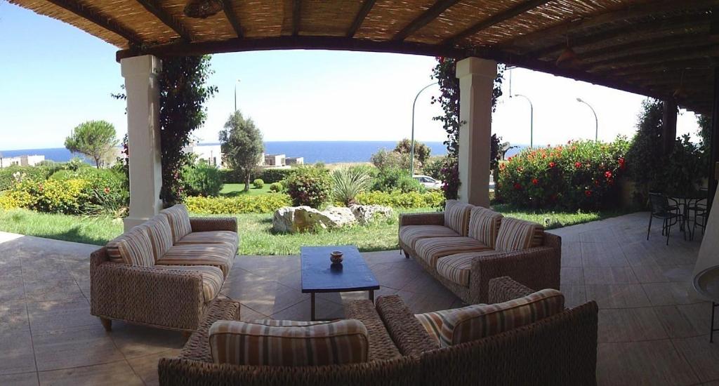 un patio al aire libre con sofás, una mesa y el océano en Villa La Torre, en Santa Cesarea Terme