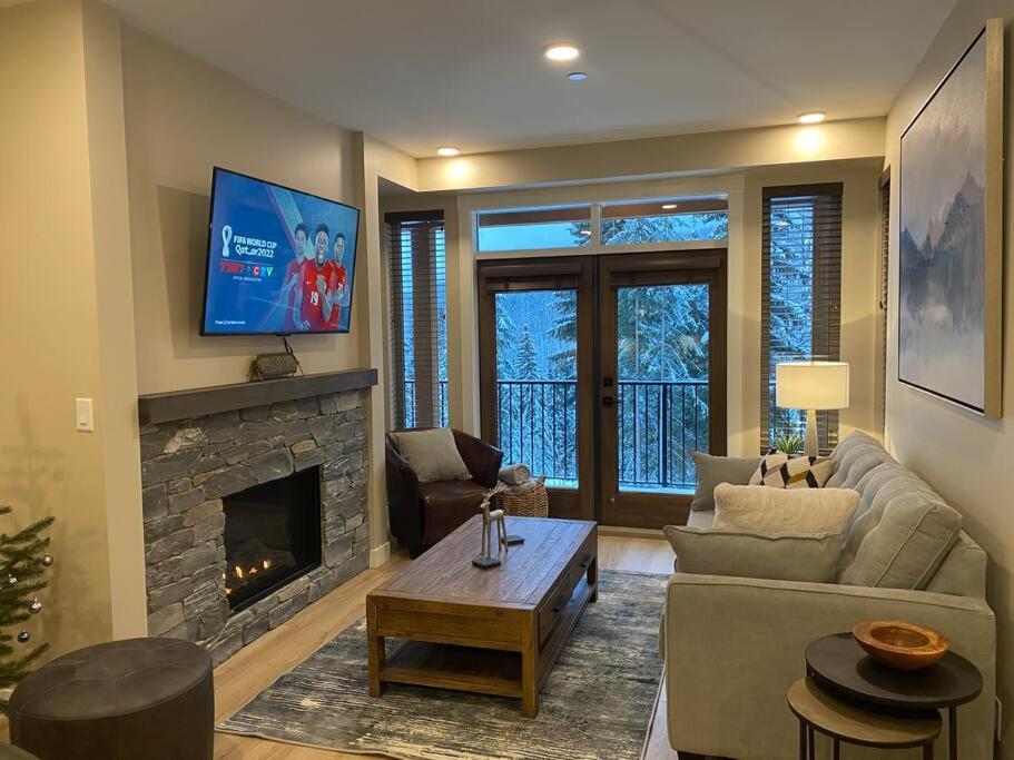 ein Wohnzimmer mit einem Sofa und einem Kamin in der Unterkunft Cozy Modern Ski-in/Ski-out, Hot Tub, Alpine Home in Sun Peaks