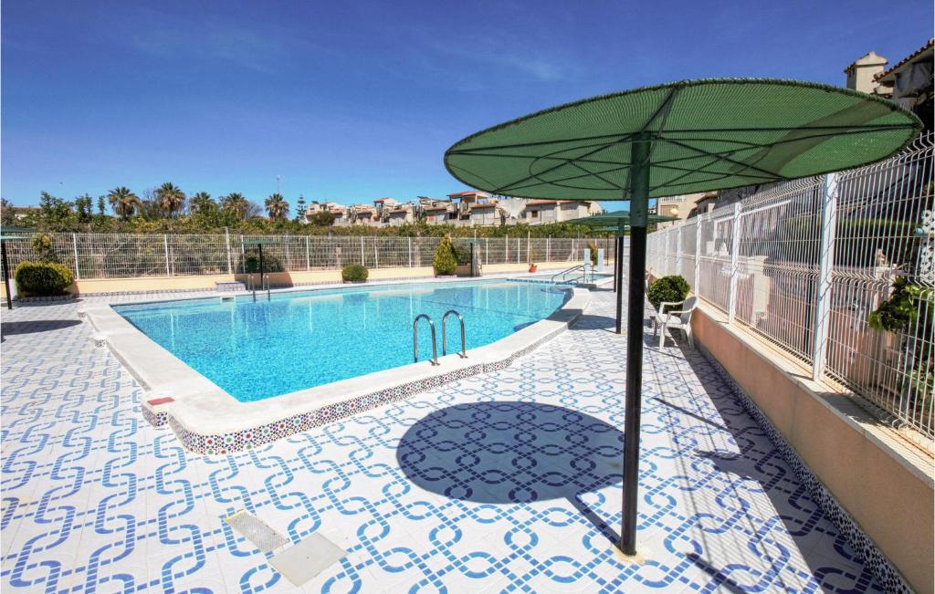 グアルダマル・デル・セグラにあるBeautiful Apartment In Guardamar Del Segura With 2 Bedrooms And Outdoor Swimming Poolのスイミングプールの横に座る緑の傘