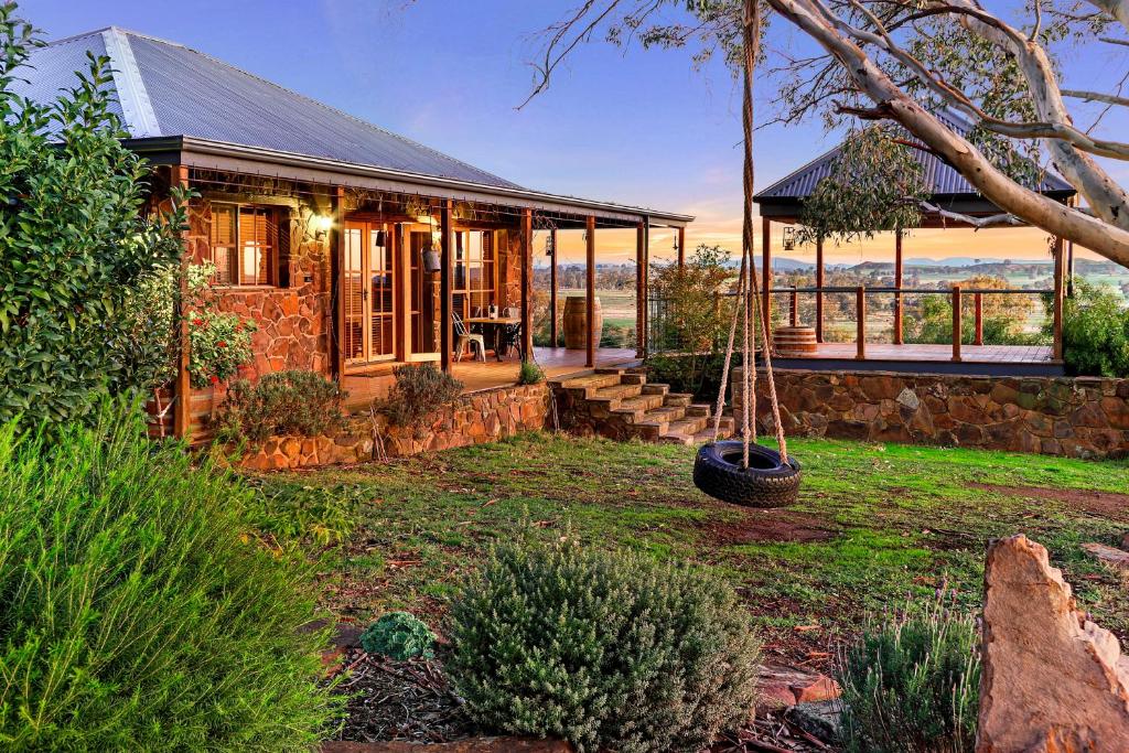 a stone house with a swing in a yard at Stone Creek Cottage in Barwite