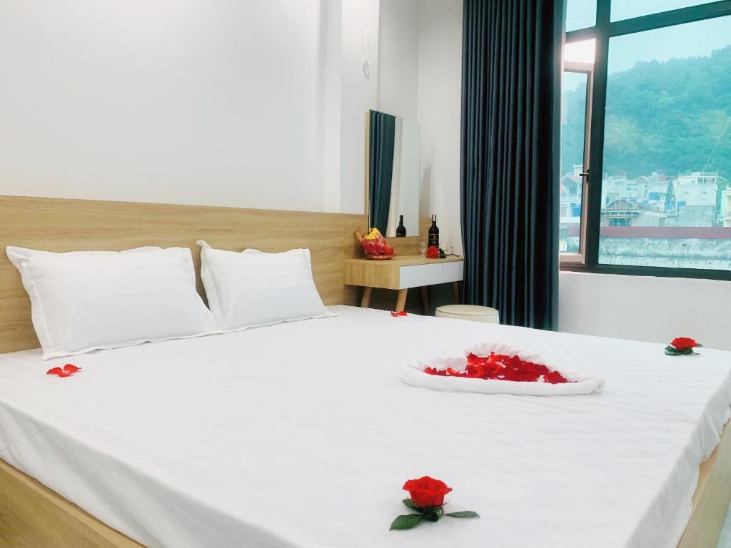 een slaapkamer met een wit bed met rode bloemen erop bij CÁT BÀ STORY HOMESTAY in Cat Ba