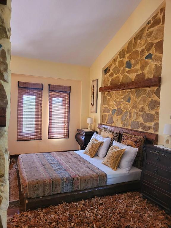 a bedroom with a bed and a stone wall at Ancient Greek Villa in Schinias