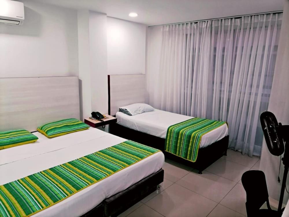 a hotel room with two beds and a chair at HOTEL DON QUIJOTE in Pereira