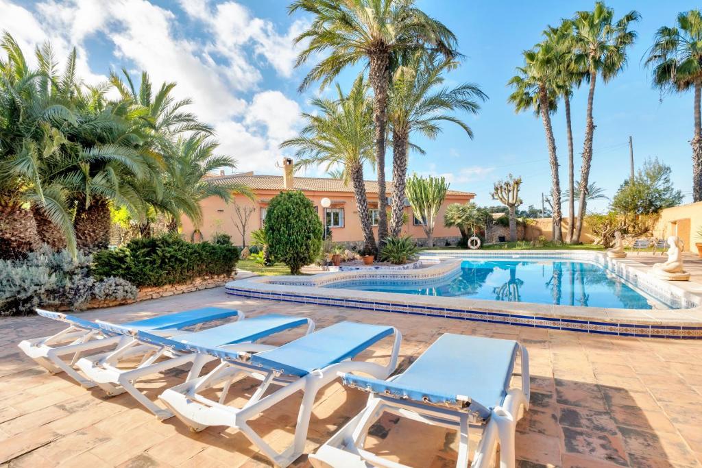 a villa with a swimming pool and palm trees at Maria I Apartment with private pool in Torrevieja