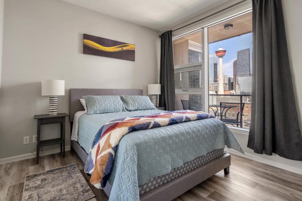 a bedroom with a bed and a large window at City View 1BR Downtown Calgary in Calgary