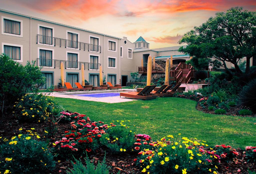 un hotel con un patio con sillas y flores en Garden Route Hotel en Mossel Bay