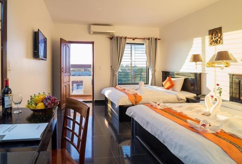 a hotel room with two beds and a table and a desk at Melody Boutique Hotel in Siem Reap