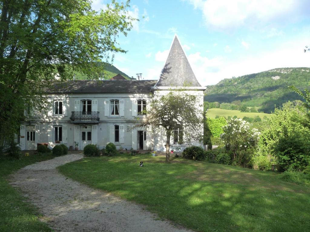 una vieja casa blanca con una torre en un campo en Résidence de Vaux en Nans-sous-Sainte-Anne