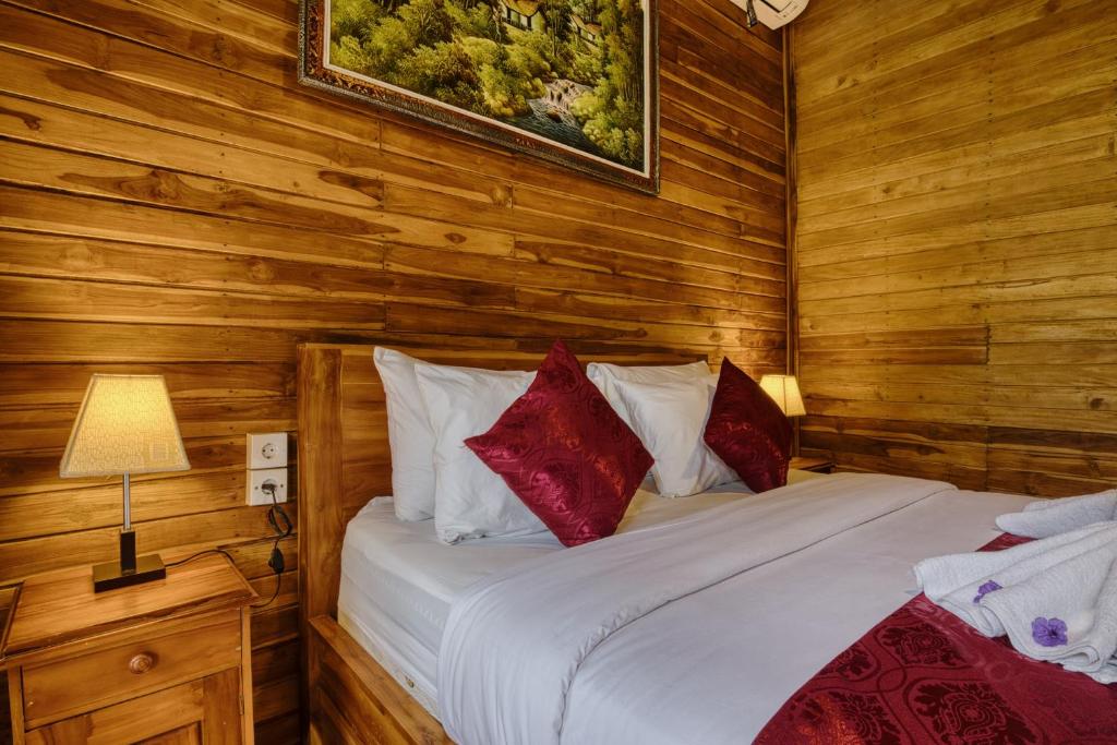 a bedroom with wooden walls and a bed with red pillows at Tegal Besung Cottage in Nusa Penida