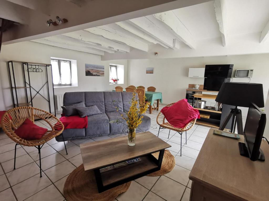 een woonkamer met een bank, stoelen en een tafel bij Equinoxe in Dragey