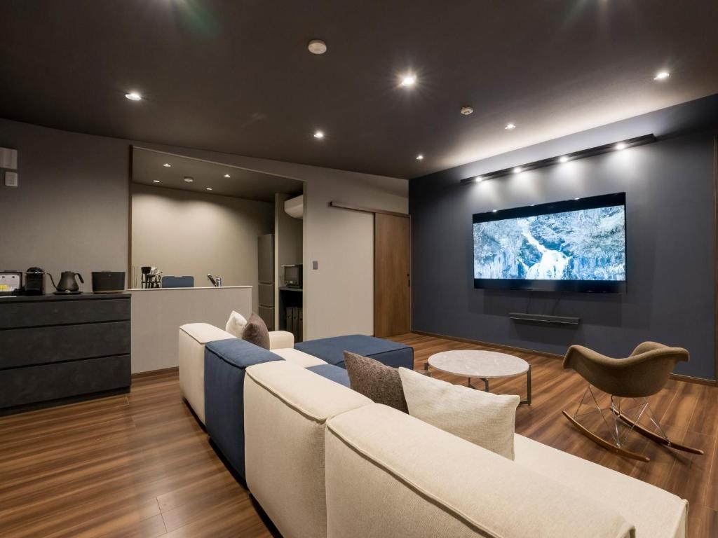 uma sala de estar com um sofá e uma televisão na parede em Rakuten STAY VILLA Yatsugatake - 102 Stylish Design - em Hokuto