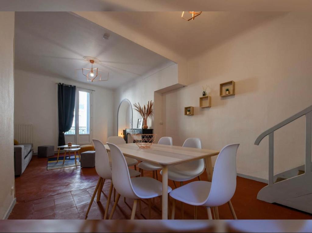 a dining room with a table and white chairs at Grand appartement de 100M2 -Allée Paul Riquet Béziers - 4chambres - Wifi- Tv connectée in Béziers