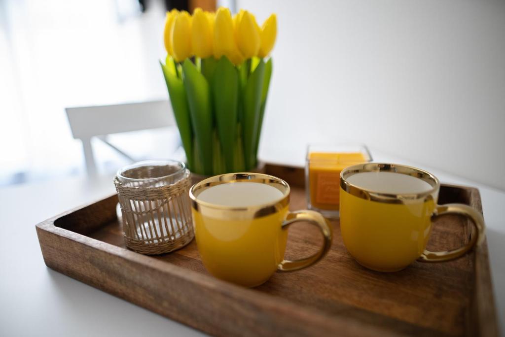 uma bandeja com duas chávenas e um vaso de flores amarelas em BAJKA em Kragujevac