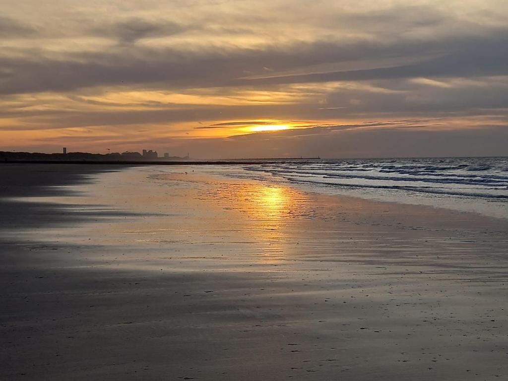 a sunset on a beach with the sun setting at Caravan Aan Zee Arnani in Middelkerke