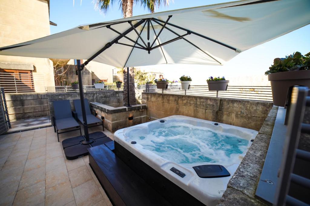 a hot tub with an umbrella on a patio at Harbour Views Duplex Maisonette with Jacuzzi Hot tub in Mġarr