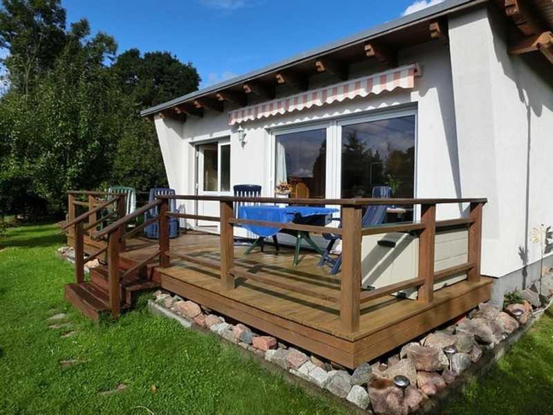 een groot houten terras met een tafel voor een huis bij Ferienhäuschen Hochufer in Lohme