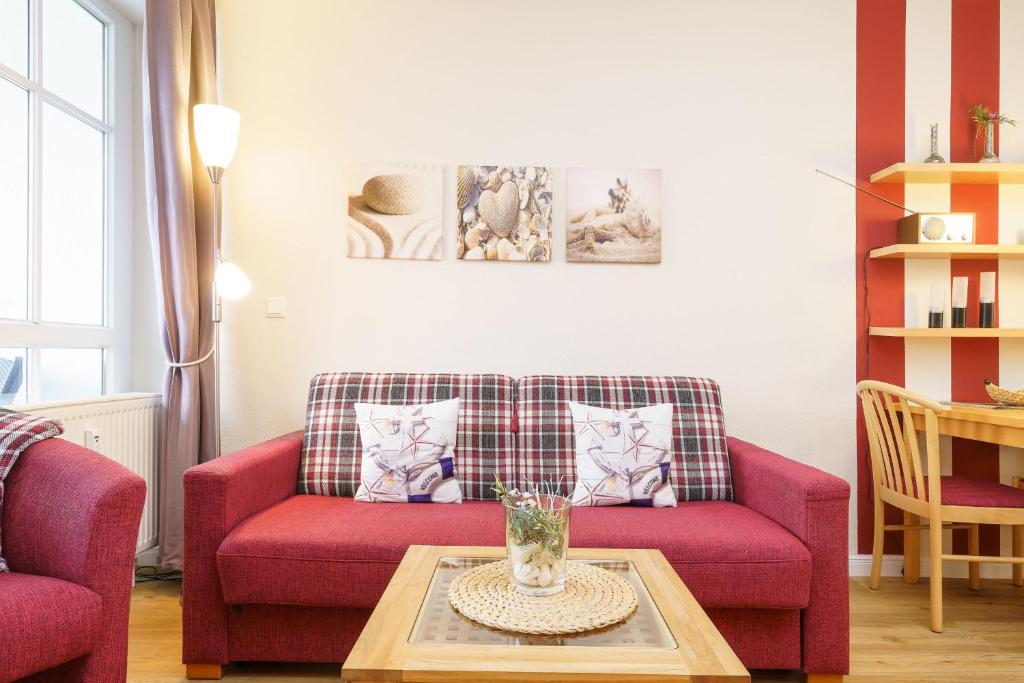 uma sala de estar com um sofá vermelho e uma mesa em Seepark Sellin FeWo AG 677 em Ostseebad Sellin