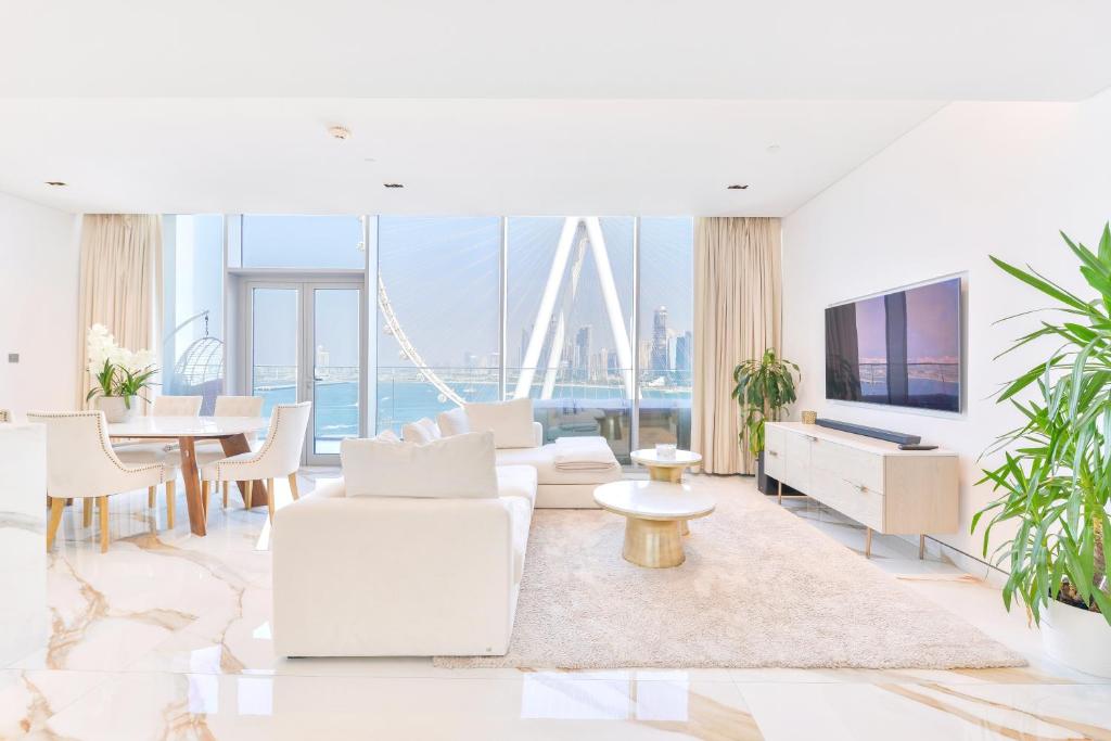 a living room with white furniture and a tv at Lavish & Equipped oceanfront 2 BR facing Ain Dubai in Dubai