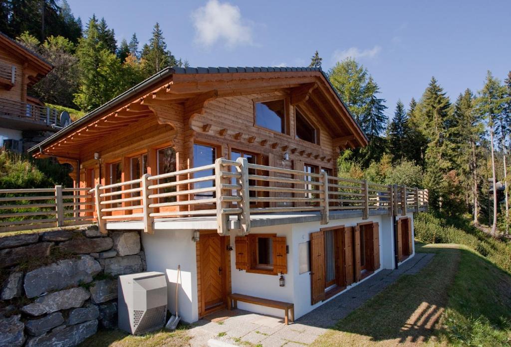 a log house with a balcony and a stone wall at Chalet la Chance in La Tzoumaz