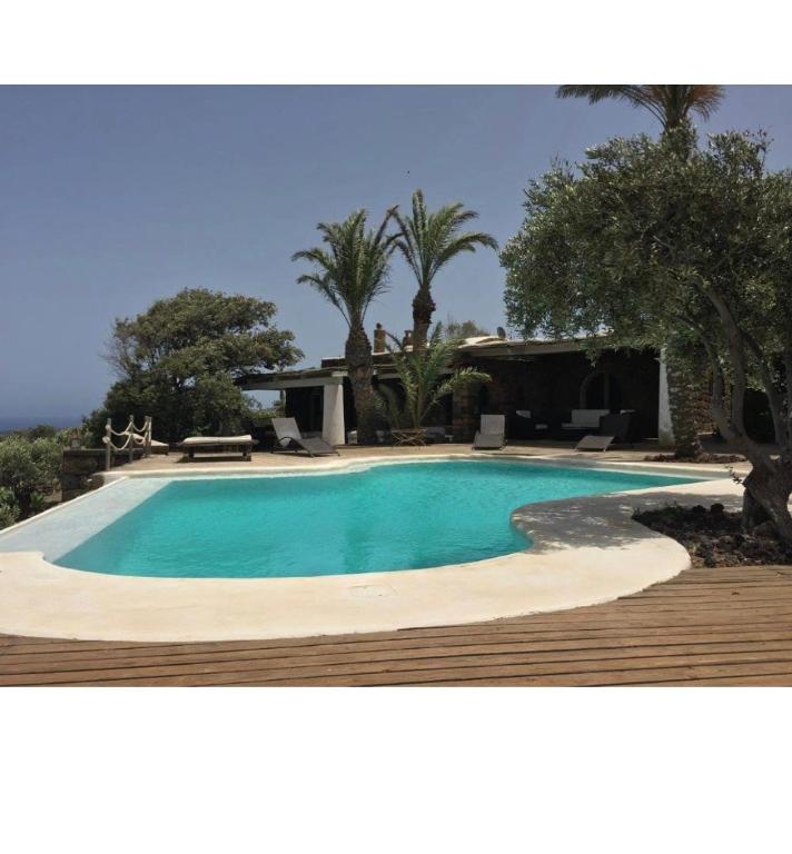 a swimming pool in a yard with a wooden deck at Intero Dammuso Pantesco in Pantelleria