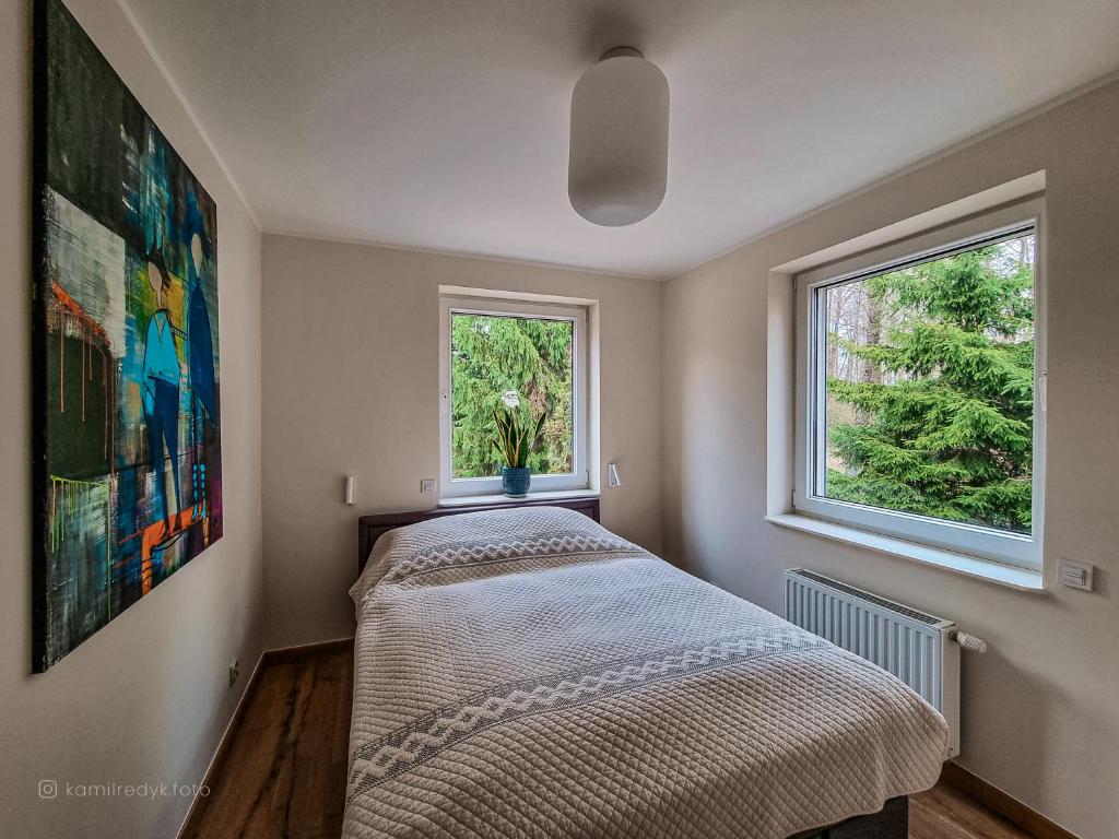 a small bedroom with a bed and two windows at Apartament VIP PROMENADA in Mrągowo